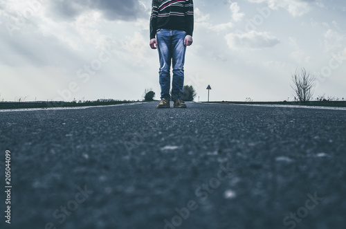 Tinted photo a guy standing in the middle of the road. Loneliness in the middle of the road