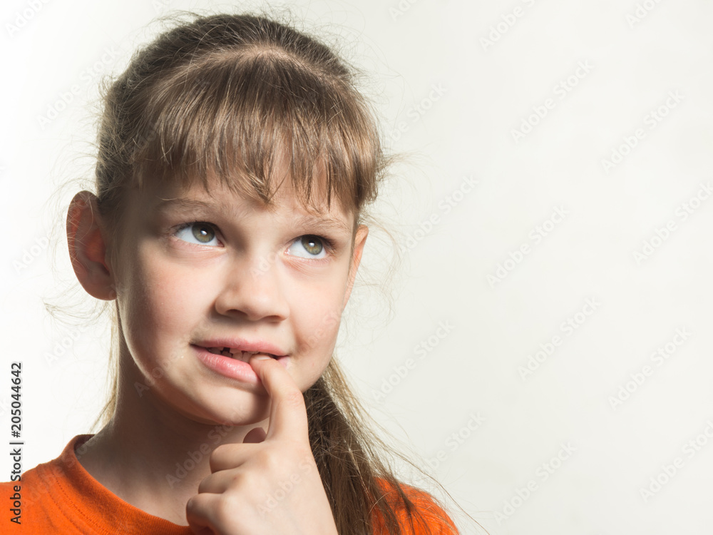 Portrait of a shy girl with a finger in her mouth, looking up thoughtfully Portrait of a shy girl with a finger in her mouth, looking up thoughtfully