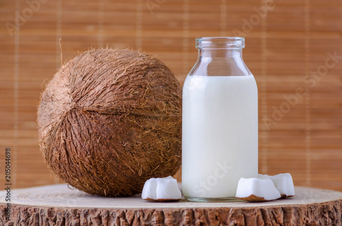 coconut milk in glass bottle on natural brown background