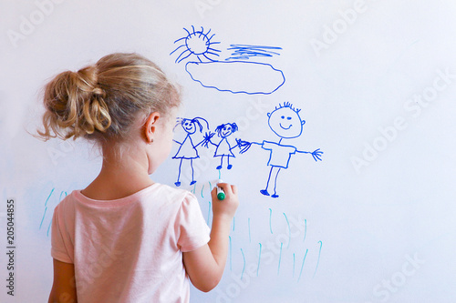 Little girl draws family on a white board.