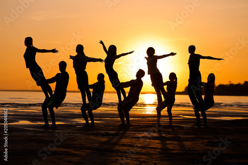 Silhouettes against the sunset are engaged in sports, fitness, yoga. A group of people.
