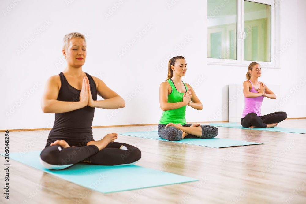 Three girls practicing yoga, Padmasana / Half lotus Position Three girls practicing yoga, Padmasana / Half lotus Position