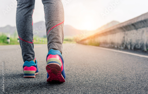 Close-up young fitness woman hiker legs at road daylight.Athlete builder muscles lifestyle.