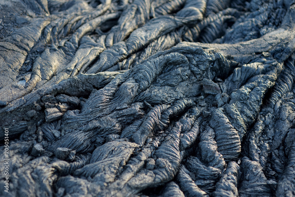 Smooth, undulating surface of frozen pahoehoe lava. Frozen lava wrinkled in tapestry-like folds and rolls resembling twisted rope on Big Island of Hawaii. Smooth, undulating surface of frozen pahoehoe lava. Frozen lava wrinkled in tapestry-like folds and rolls resembling twisted rope on Big Island of Hawaii.