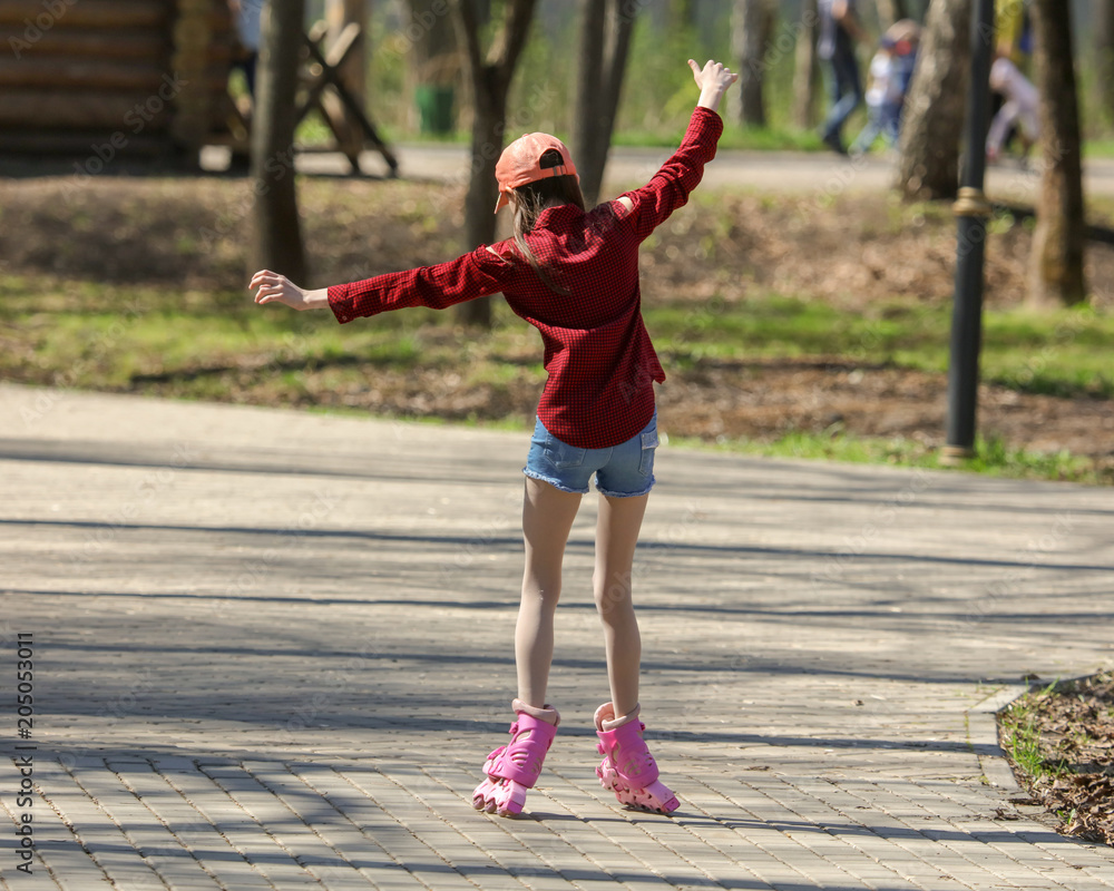 Girl skating on pink rollers in the park