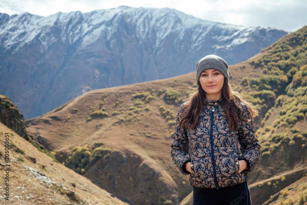 beautiful girl stands on the background of mountains