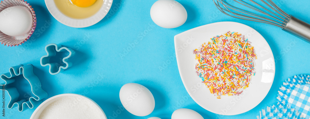 Eggs, flour, sugar and ingredients for baking on a blue background flat fork on top of a long banner