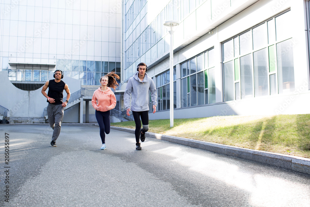 Obraz premium Young people go in for sports in the city. Running in the city. Friends are running around town