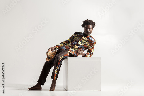 Barefooted african man uncomfortble sit on cube