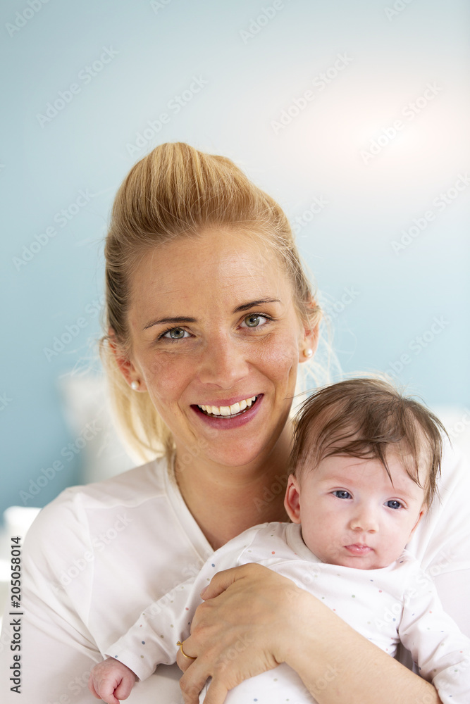 young, beautiful and blond mother is holding her baby in her arms young, beautiful and blond mother is holding her baby in her arms
