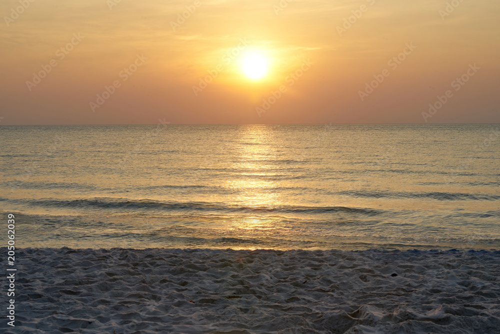 Sun on sky with sea and sand on beach with warm orange light