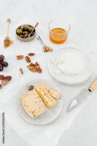 Cheese platter with olives, nuts, grapes and honey on a marble table. photo