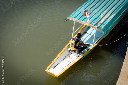 A young Asian backpacker tourist is enjoying a boat ride on the river.Holidays and nature concepts © Chayanin Wongpracha