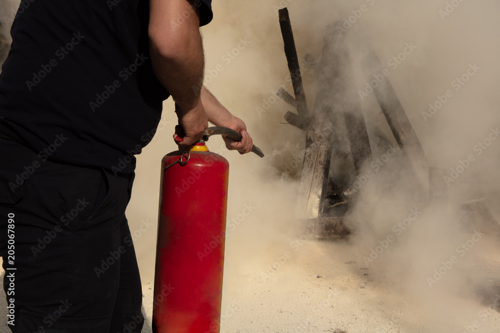 Fototapeta premium Young man pointing a fire extinguisher forwards..