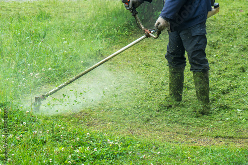 The gardener cutting grass by lawn mower