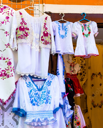 Beautiful bright ethnic shirts and tablecloths with traditional Hungarian embroidery in a street store. © v_tynka