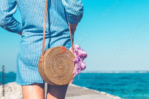 Woman with fashionable stylish rattan bag outside. Tropical island of Bali, Indonesia. Rattan and silk. photo