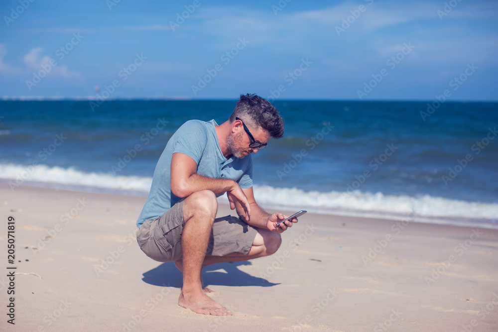 Young man using smartphone on the beach Young man using smartphone on the beach