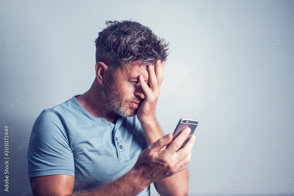 Handsome young man using mobile phone feel sad