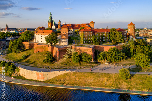 Krakow  Poland. Wawel Hill  royal Cathedral and castle. Aerial view in sunset light. Vistula River and far view of St. Mary  Mariacki  church on the left. Riverbank with promenade and walking people