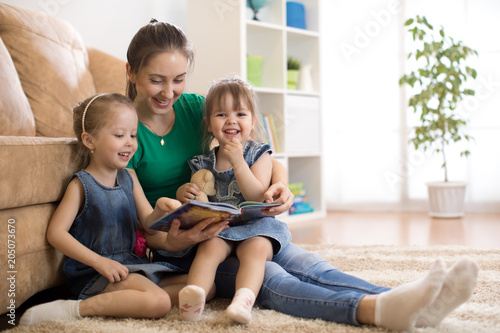 Family mom and daughters relaxing at home and reading book
