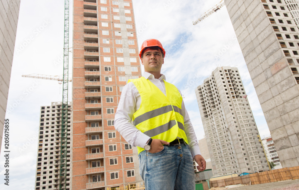 Portrait of young businessman in hardhat standing on building site Portrait of young businessman in hardhat standing on building site
