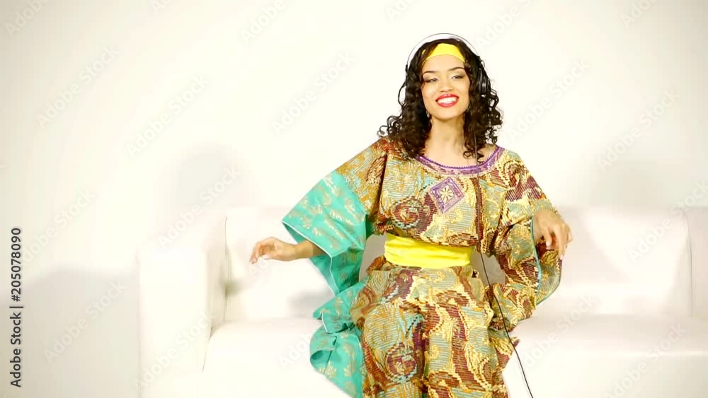 young and cute woman dressed in traditional dress sings sitting on the couch young and cute woman dressed in traditional dress sings sitting on the couch