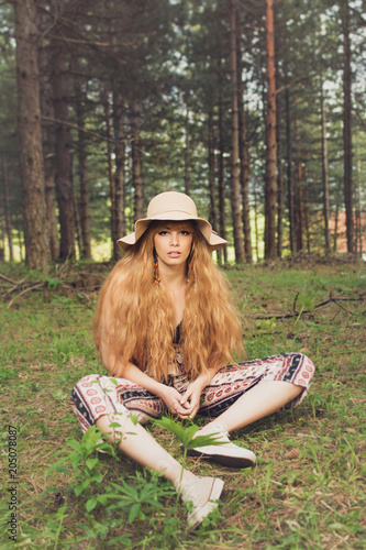 Beautiful bohemian blonde woman in forest, sitting and posing. Natural lighting, no retouch, matte filter.