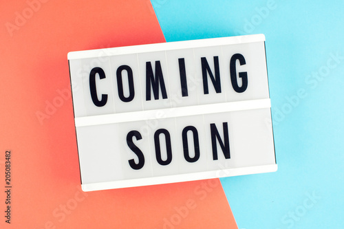 Coming soon - text on a display lightbox on blue and red bright background.