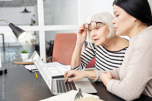 Technology in learning. Pensive tutor and mature student communicating and staring at screen