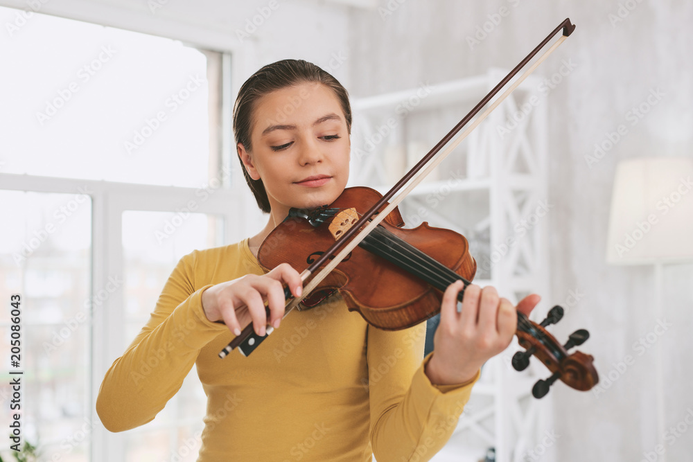 Be attentive. Pretty brunette bowing head while looking at her instrument Be attentive. Pretty brunette bowing head while looking at her instrument