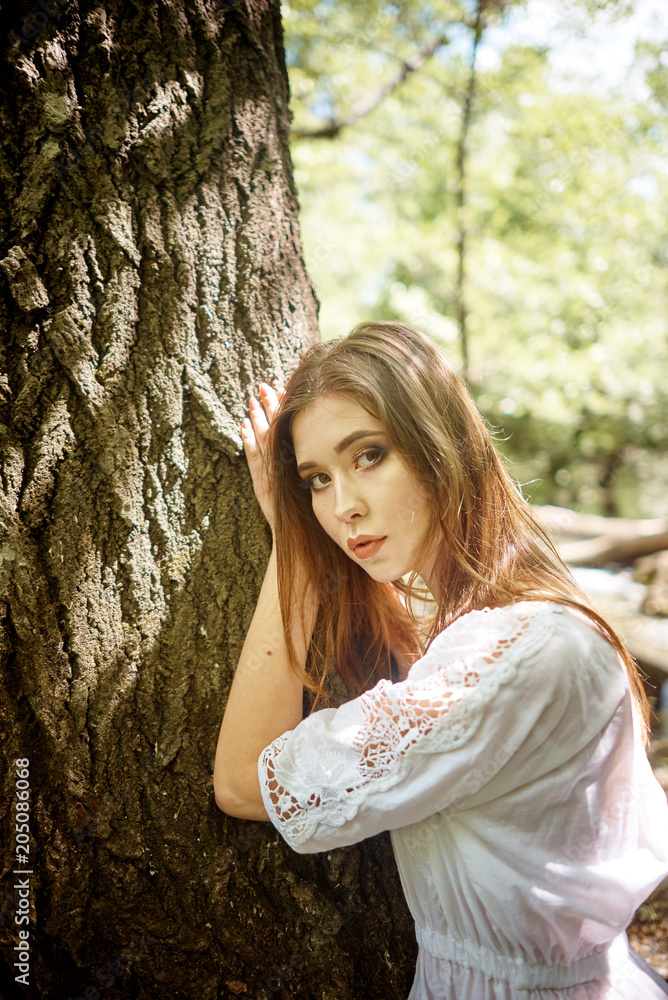 Young pretty woman in a white dress walking and posing in a forest near the river Young pretty woman in a white dress walking and posing in a forest near the river