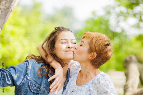 Mother and daughter hug each other, happy and smiling, summer out in the park 