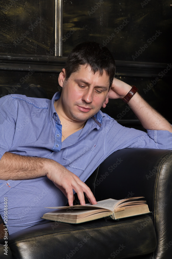 Young man is lying on the sofa and is reading a book. Close-up. Young man is lying on the sofa and is reading a book. Close-up.