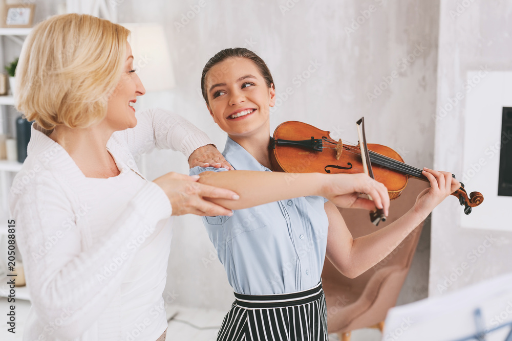 Play with pleasure. Beautiful brunette keeping smile on her face while playing classical melody Play with pleasure. Beautiful brunette keeping smile on her face while playing classical melody