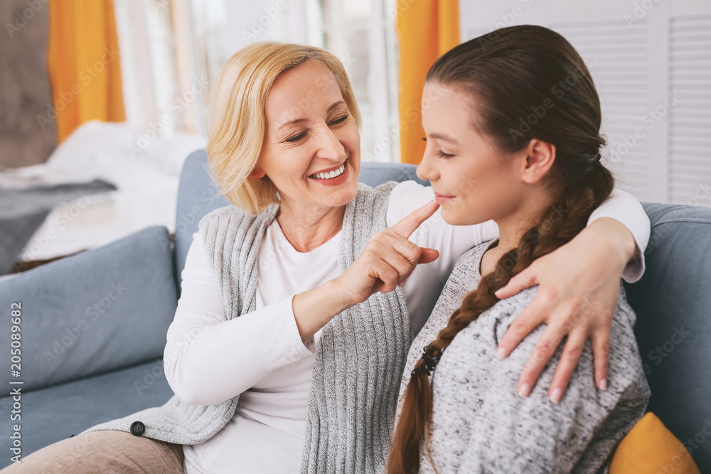 Natural beauty. Joyful mature female person keeping smile on her face while embracing her kid Natural beauty. Joyful mature female person keeping smile on her face while embracing her kid