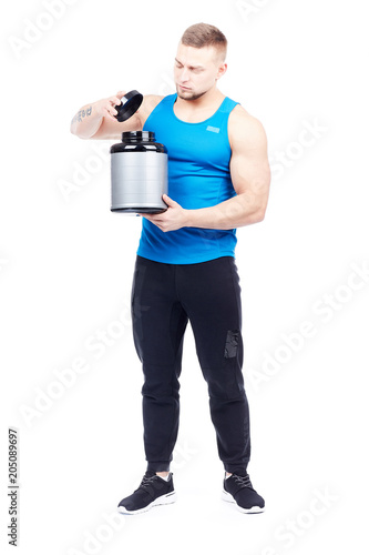Isolated portrait of well-muscled athletic man holding container with sports nutrition