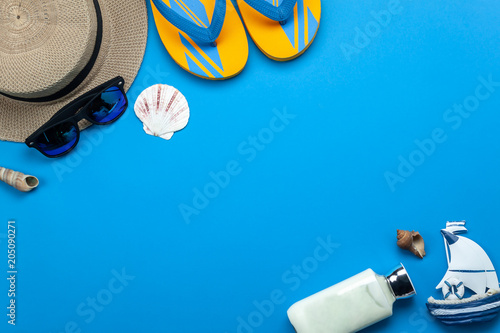 Table top view aerial image of fashion for travel in summer holiday background.Flat lay accessories clothing for traveler.Sun block & cloth on modern rustic blue paper wallpaper.Space for content.