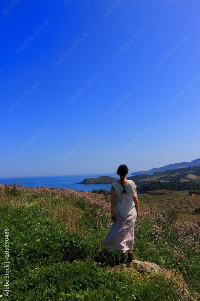 Young woman in dress admiring a Mediterranean landscape, Pyrenees orientales in southern of France