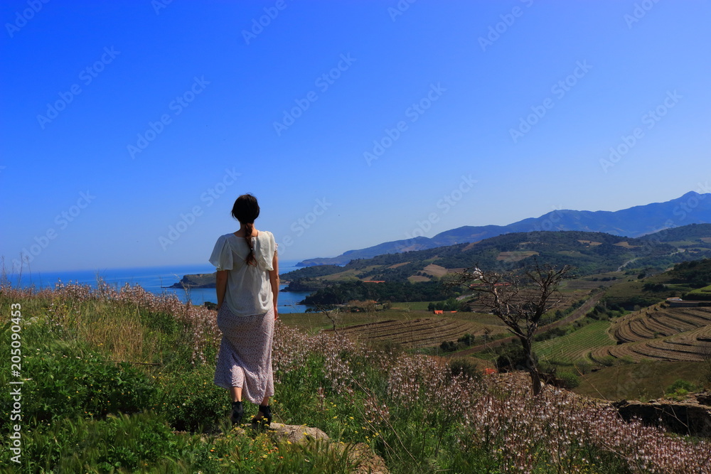 Young woman in dress admiring a Mediterranean landscape, Pyrenees orientales in southern of France