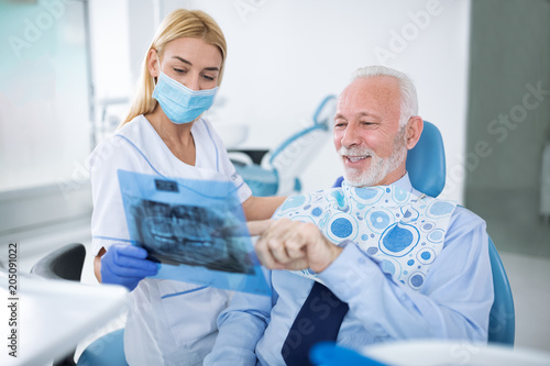 Dentist with sterile mask and dental instruments held exam teeth of patient