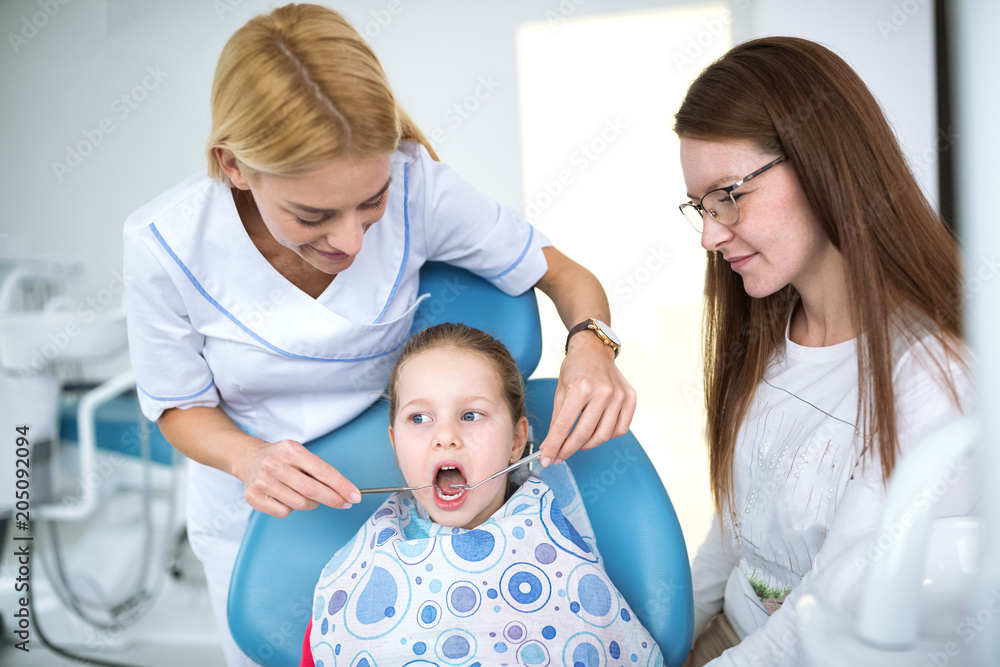 Dentist with sterile mask and dental instruments held exam teeth of patient Dentist with sterile mask and dental instruments held exam teeth of patient