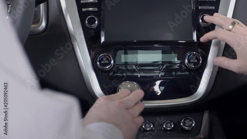 Two young men is testing new car in showroom, sitting inside, seller and customer touching details of automobile with hands, interact before buying at auto center. Concept: auto salon, modern