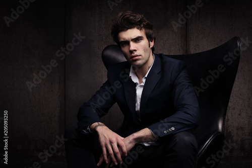 Portrait of a beautiful young man sitting in a chair. Stylish in appearance © Bakulov