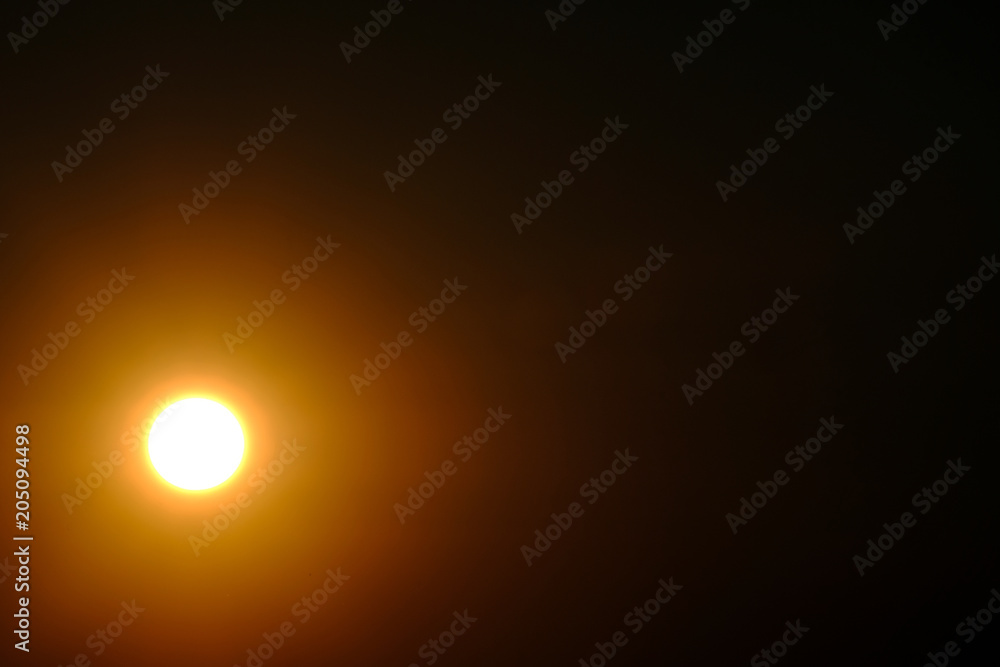 A bright sun or moon in the coner on a dark sky. Designer background.
