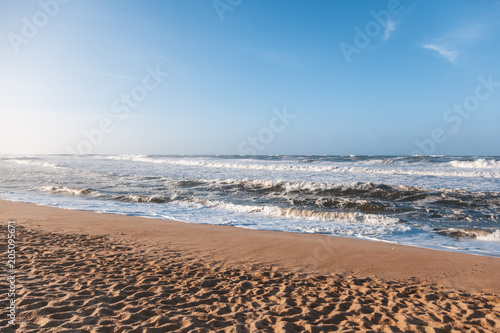 Beautiful sandy ocean coast, waves and blue sky