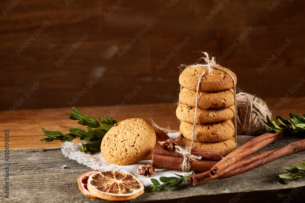 Christmas composition with pile of cookies, cinnamon and dried oranges on light wooden background, close-up. Christmas composition with pile of cookies, cinnamon and dried oranges on light wooden background, close-up.