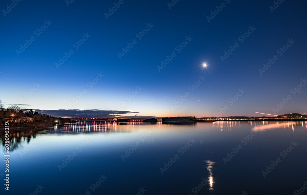 Dawn on a calm river with moon and air traffic