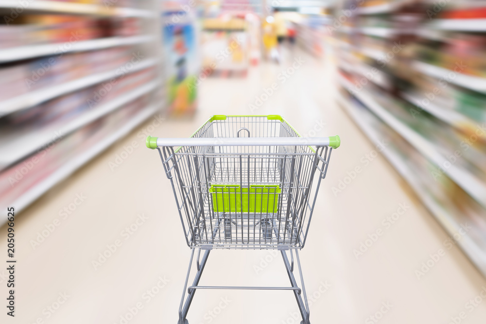 shopping cart with abstract motion blur supermarket discount store aisle and product shelves interior defocused background