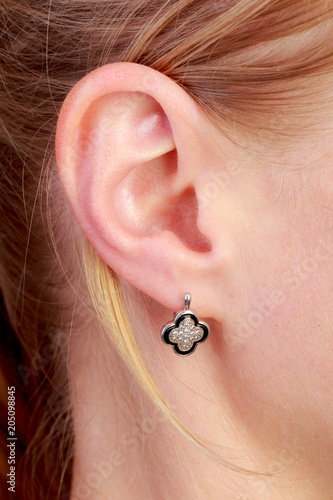 Ear female with earring, blonde, European, light skin, close-up.